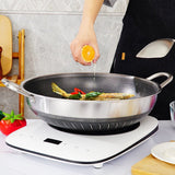 Person cooking fish in a wok on a portable stove with a kitchen setting in the background.
