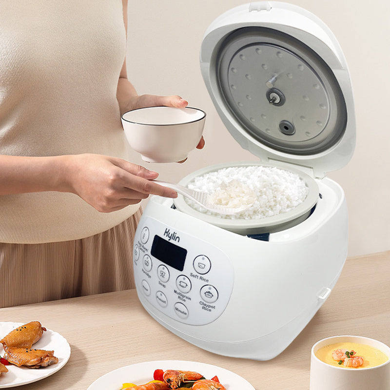 Person using a white rice cooker with food on a table